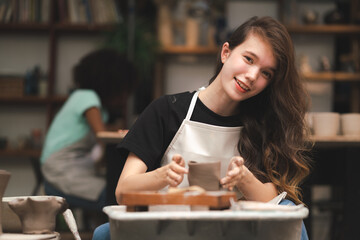 happy smiling girl having fun to learning and work with craft art of clay hand-made workshop in ceramic studio, little ceramist enjoy in creative handcraft hobby with pottery artisan school class