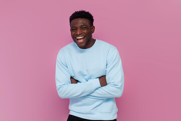 cheerful african american man in blue sweater laughing on pink isolated background