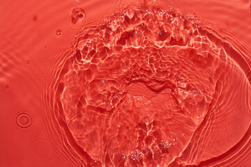 Water red surface abstract background. Waves and ripples texture of cosmetic aqua moisturizer with bubbles.