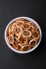 Round slices of sweet banana on a dark concrete background