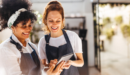 Female restaurant employees using a mobile app on a tablet for restaurant management