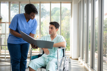 Nurse assisting explains therapy to a disabled patient in a wheelchair at the hospital. medical and health care concept