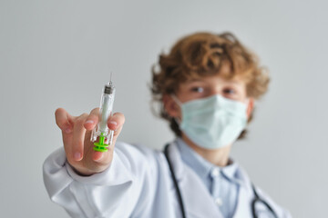 Boy doctor with plastic syringe on white background