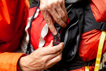 man closes backpack with clasp, close-up of hiking backpack
