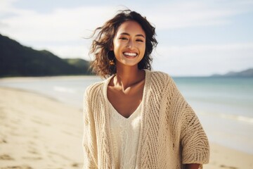 Happy woman enjoying a beach vacation, smiling and standing on the sand by the sea