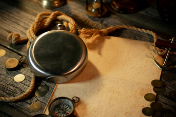 Metal flask with a sheet of paper for text or map. Treasure island concept on a wooden table background