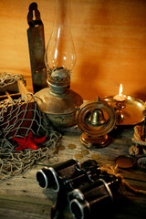 Treasure island concept on a wooden table background. Sea star and kerosene lamp on fish net 