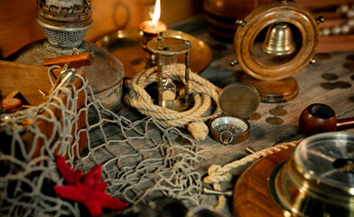 Treasure island concept on a wooden table background. Sea star and hourglass on fish net between of marine elements