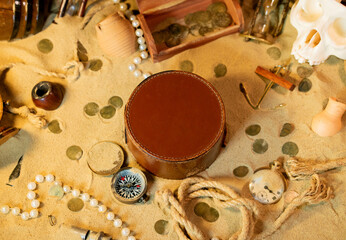 Treasure island theme. Vintge round box on the sand among shells, stones and marine elments. Frame...