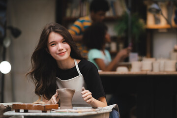 Fototapeta premium happy smiling girl having fun to learning and work with craft art of clay hand-made workshop in ceramic studio, little ceramist enjoy in creative handcraft hobby with pottery artisan school class