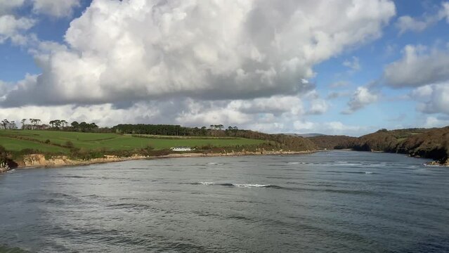 Panning shot of the beautiful Erme Estuary coastline at high tide with Wonwell, Coastguards and Mothecombe beaches along with surfers catching waves - Nr Kingston, Devon, UK