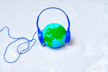 Earth Globe with Blue Headphones Isolated on Concrete Background