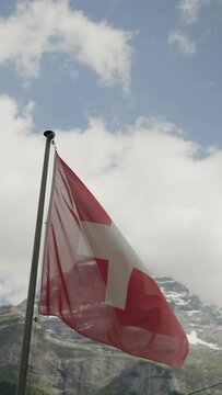Swiss flag waving in the wind in front of high mountain