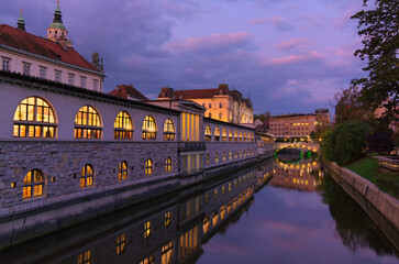 Sunrise landscape view of ancient city center of Ljubljana. Embankment of Ljubljanica River with illuminated colorful historic houses. Tavel and tourism concept