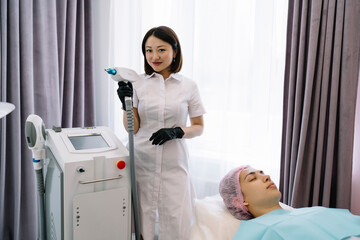 Female cosmetologist with neodymium laser preparing for procedure