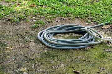Garden water pile hose on the floor grounds with a green grass in the garden.