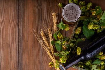 Beer bottle and glass with hop cones, Fresh craft beer and ingredients, copy space on wooden background