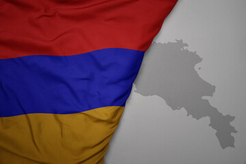 big waving national colorful flag and map of armenia on the gray background.