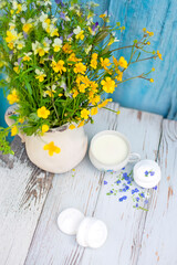 cup with natural homemade milk and sweet marshmallows on a wooden background. A bouquet of wildflowers and summer mood, natural food. Non-Homogenized Milk