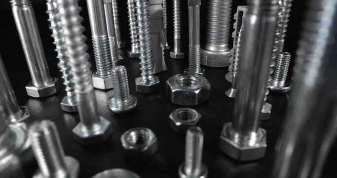 metal screws, bolts and fasteners on black background. slider shot