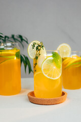 Drink with orange lemon and lime in glass transparent glasses on a concrete background. Lemonade with ice. Front view