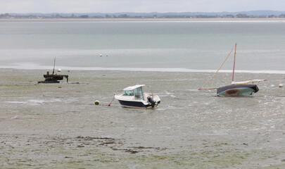 stranded boats and motorboat in Normandy in France during low tide