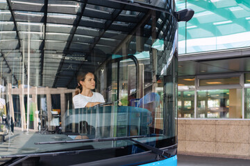 Young woman driving a shuttle bus at a suburban bus station, female shuttle bus driver occupation...