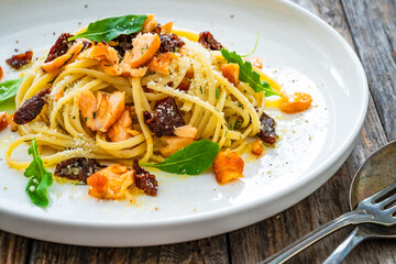 Linguine with salmon and sun dried tomatoes on wooden table
