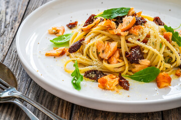 Linguine with salmon and sun dried tomatoes on wooden table
