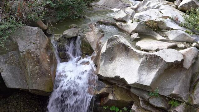 Splashing litte waterfall at river in the Swiss Alps at hiking trail to Grimsel mountain pass on a late summer day. Movie shot September 19th, 2023, Grimsel mountain pass, Canton Bern, Switzerland.
