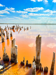 Broken wooden fence, salt lake, natural mud lake. Crimean Salt lake. Blue sky, red water.