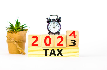 2024 tax new year symbol. Businessman turns a wooden cube and changes words Tax 2023 to Tax 2024....