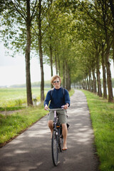 Fototapeta premium A Boy Riding His Bike Along The Dutch Canals; Houten, The Netherlands