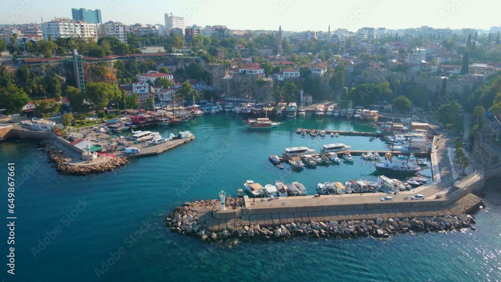 Wall mural In this aerial stock video, the timeless beauty of the Old Port of Antalya comes to life. The camera soars above the historic harbor nestled within the old town of Antalya, Turkey. The scene showcases - Wall murals