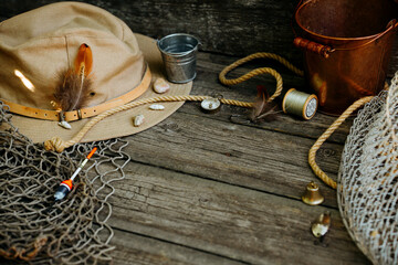 Fishing theme. Fisher cap with hooks, bucket, fishing buoy, compass and fish string on wooden...