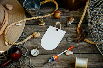 Fishing theme. Label with hooks, bucket, fishing buoy, compass and fish string on wooden...
