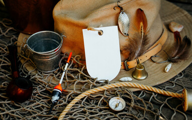 Fishing theme. Label on fisher cap with hooks, bucket, fishing buoy, compass and fish string on...