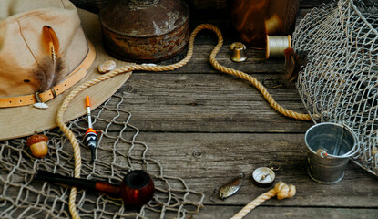 Fishing theme. Fisher cap with hooks, bucket, fishing buoy, compass and fish string on wooden...