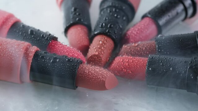 Red lipsticks make up close up background with smoke and water drops, different shades of pink bronze lipstick, studio advertising macro beauty concept.