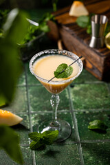 Melon margarita cocktail with mint in glass on dark green ceramic tile background