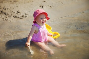 A Baby Girl Sits At The Edge Of Lac Bellevue With A Shovel In Her Hand; Alberta, Canada