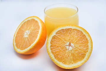 Orange juice in a glass glass and the fruit of oranges. Refreshing drink on a white background of fruit.