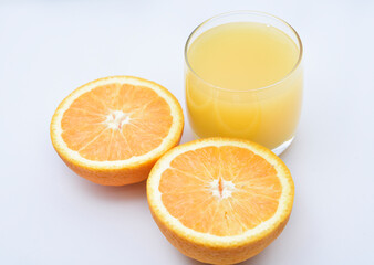 Orange juice in a glass glass and the fruit of oranges. Refreshing drink on a white background of fruit.