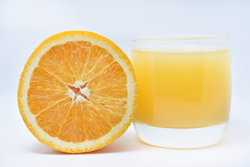 Orange juice in a glass glass and the fruit of oranges. Refreshing drink on a white background of fruit.