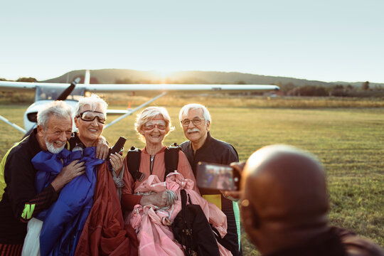 Group of senior friends getting their picture taken after skydiving together for their first time