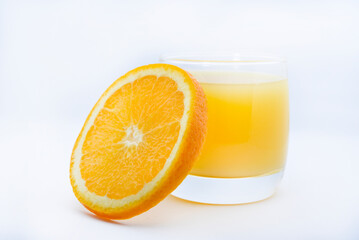 Orange juice in a glass glass and the fruit of oranges. Refreshing drink on a white background of fruit.