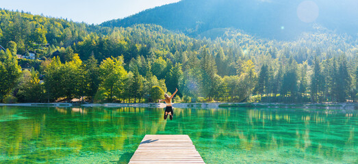 Happy woman jumping on pier, breathtaking landscape with emerald lake in mountain- Slovenia- freedom,travel,tourism,healthy lifestyle concept