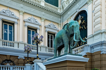 A large elephant statue, stands on an intricately patterned pedestal in front of a ornately...