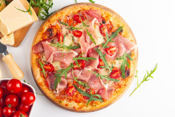 Pizza with prosciutto, ham, arugula, tomatoes, pesto, cheese and parmesan. Italian cuisine. 