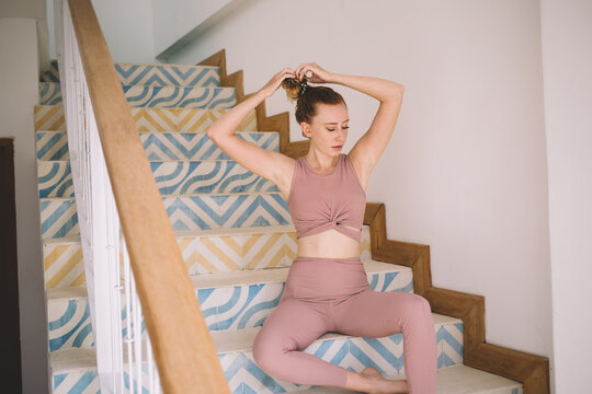 Slim woman resting on steps and loosening hair